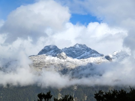 another mountain peaks out behind the clouds