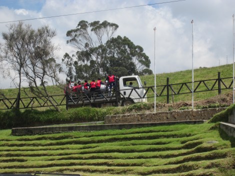 truck with a large silver milk tank on the back (although you can hardly see it as the school kids are riding on back)